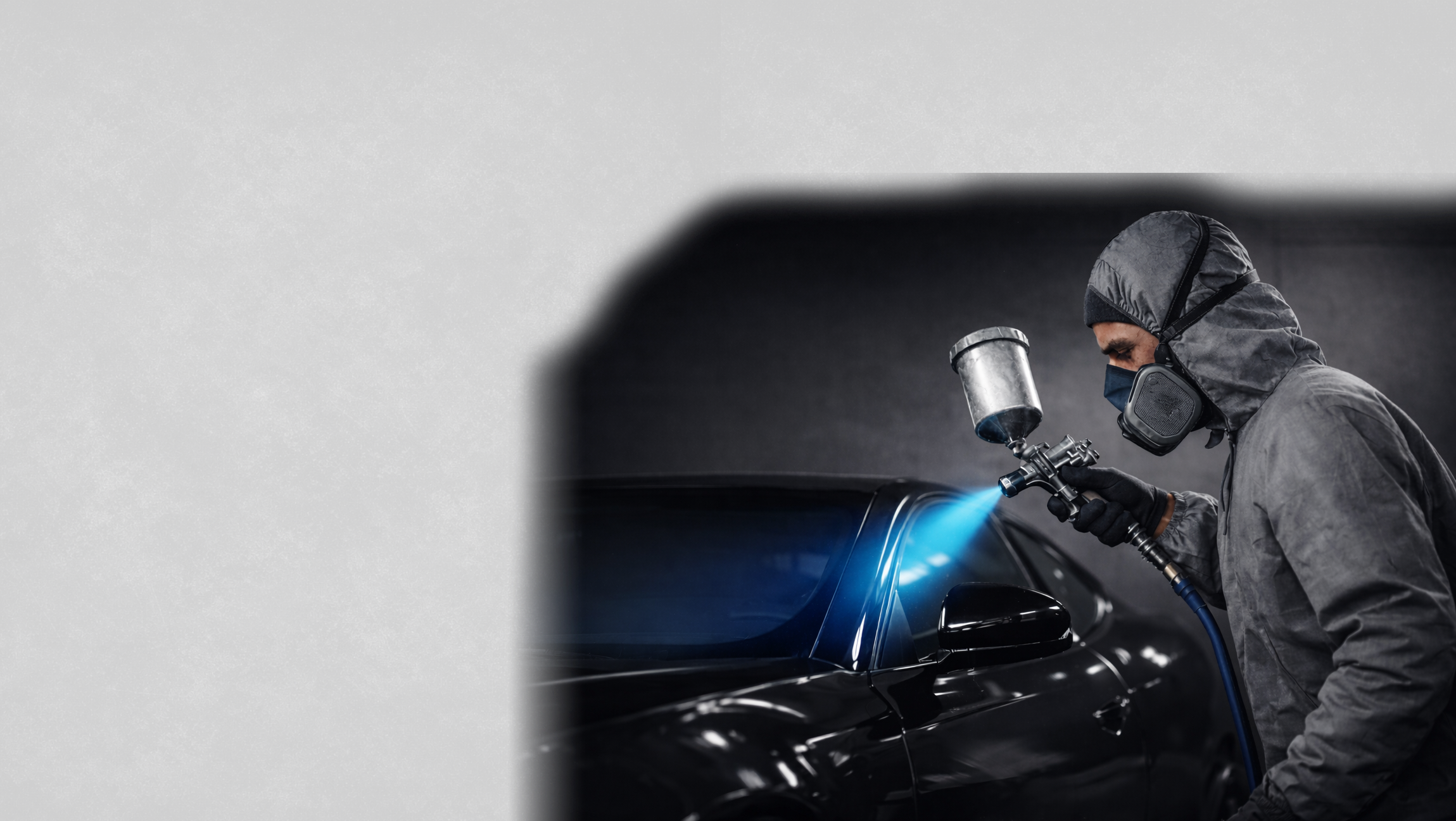Fahrzeuglackierer sprüht mit einer Lackierpistole Lack auf ein Auto